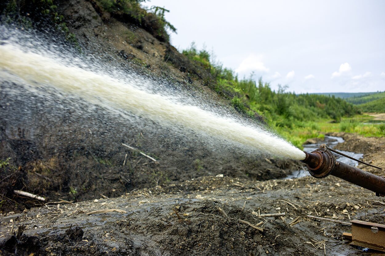 The giant monitor is spraying water onto the frozen muck and the permafrost is melting away at the Boneyard Alaska.