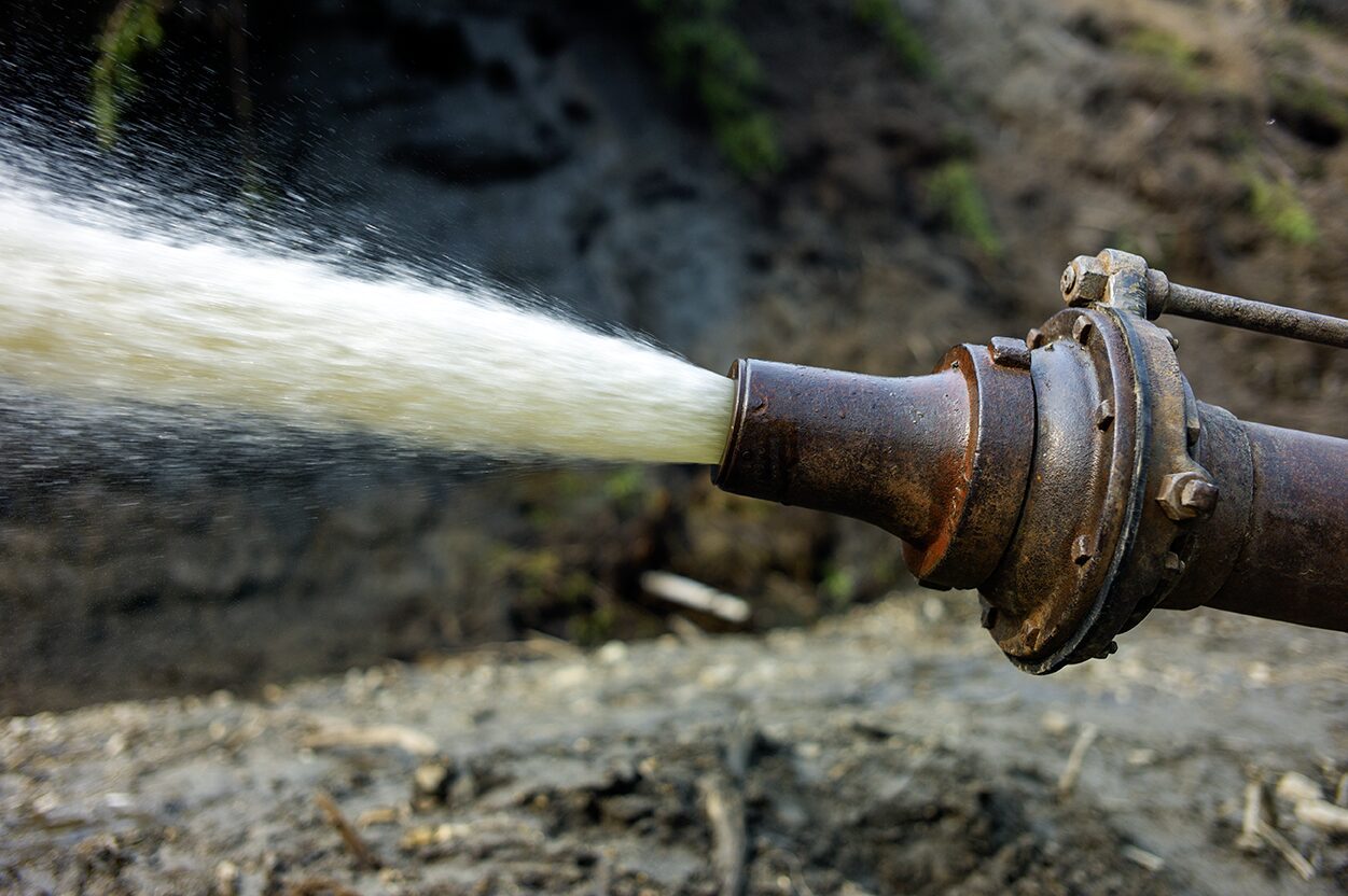 The giant monitor is spraying water onto the frozen muck and the permafrost is melting away at the Boneyard Alaska.. Placer mining for gold photo giant monitor water stream photo of the nozzle