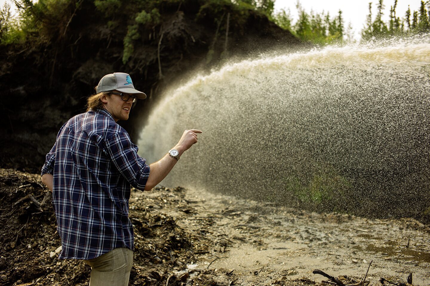 Kinzey Reeves pointing to where the water should go, the Boneyard Alaska, outside at the dig site where animal bones from the last Ice Age have been discovered. Kinzey is the writer for the documentary film Boneyard Alaska, photographed here on location.